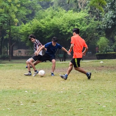 Yeni Delhi, Hindistan - 01 Temmuz 2018: Kötü bir futbol sahasında bölgesel Derby şampiyonasında yerel futbol takımının futbolcuları. Stadyumun çimen yeşili sahasında sıcak bir futbol maçı var.