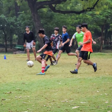 Yeni Delhi, Hindistan - 01 Temmuz 2018: Kötü bir futbol sahasında bölgesel Derby şampiyonasında yerel futbol takımının futbolcuları. Stadyumun çimen yeşili sahasında sıcak bir futbol maçı var.