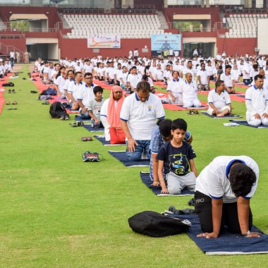 Yeni Delhi, Hindistan, 21 Haziran 2022 - Uluslararası Yoga Günü 'nde Delhi' deki Yamuna Spor Kompleksi 'nde grup Yoga egzersiz oturumu, kriket stadyumunda yoga derslerine katılan büyük bir grup yetişkin