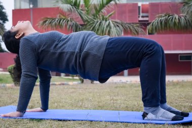 Young Indian woman practicing yoga outdoor in a park. Beautiful girl practice basic yoga pose. Calmness and relax, female happiness. Basic Yoga poses outdoor