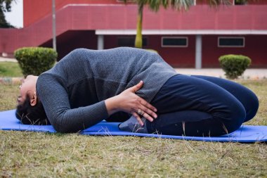 Young Indian woman practicing yoga outdoor in a park. Beautiful girl practice basic yoga pose. Calmness and relax, female happiness. Basic Yoga poses outdoor