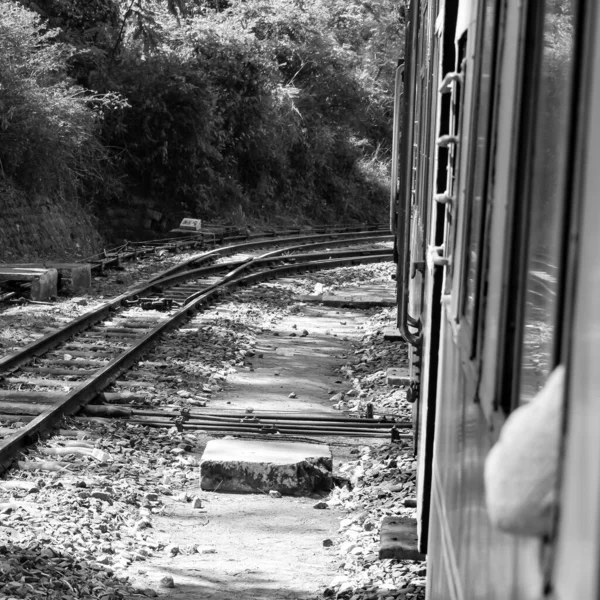 Toy Train moving on mountain slope, beautiful view, one side mountain, one side valley moving on railway to the hill, among green natural forest. Toy train from Kalka to Shimla in India-Black and White
