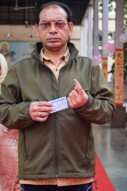 New Delhi, India - December 04 2022 - Unidentified people showing their ink-marked fingers after casting votes in front of polling booth of east Delhi area for MCD local body Elections 2022
