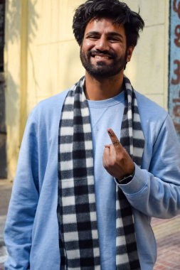 New Delhi, India - December 04 2022 - Unidentified people showing their ink-marked fingers after casting votes in front of polling booth of east Delhi area for MCD local body Elections 2022