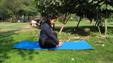 Young Indian woman practicing yoga outdoor in a park. Beautiful girl practice basic yoga pose. Calmness and relax, female happiness. Basic Yoga poses outdoor 