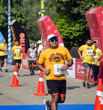 Yeni Delhi, Hindistan - 16 Ekim 2022 - Bitmek üzere olan maraton katılımcılarının bitiş çizgisini geçmek üzere olan Delhi Yarı Maratonu 2022