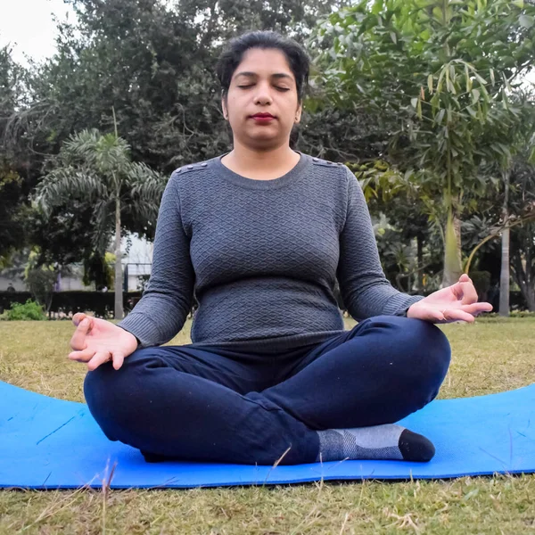 Young Indian woman practicing yoga outdoor in a park. Beautiful girl practice basic yoga pose. Calmness and relax, female happiness. Basic Yoga poses outdoor