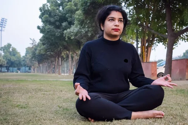 Young Indian woman practicing yoga outdoor in a park. Beautiful girl practice basic yoga pose. Calmness and relax, female happiness. Basic Yoga poses outdoor