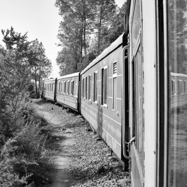 Toy Train moving on mountain slope, beautiful view, 1 side mountain, 1 side valley moving on railway to the hill, among green natural forest. Toy train from Kalka to Shimla in India-Black and White