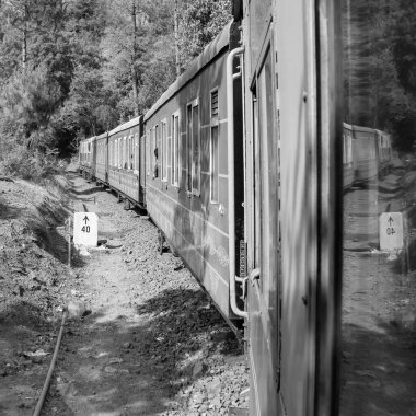 Toy Train moving on mountain slope, beautiful view, 1 side mountain, 1 side valley moving on railway to the hill, among green natural forest. Toy train from Kalka to Shimla in India-Black and White