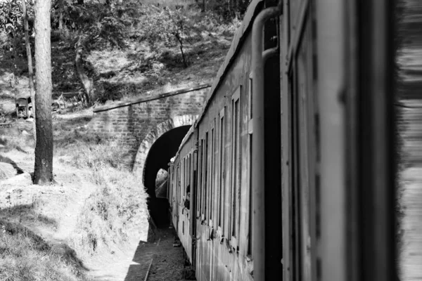Toy Train moving on mountain slope, beautiful view, 1 side mountain, 1 side valley moving on railway to the hill, among green natural forest. Toy train from Kalka to Shimla in India-Black and White