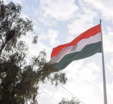 India flag flying high at Connaught Place with pride in blue sky, India flag fluttering, Indian Flag on Independence Day and Republic Day of India, tilt up shot, Waving Indian flag, Har Ghar Tiranga