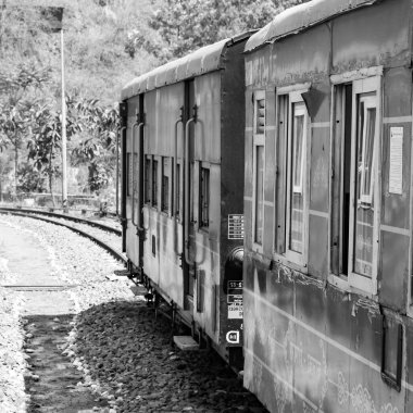 Toy Train moving on mountain slope, beautiful view, 1 side mountain, 1 side valley moving on railway to the hill, among green natural forest. Toy train from Kalka to Shimla in India-Black and White