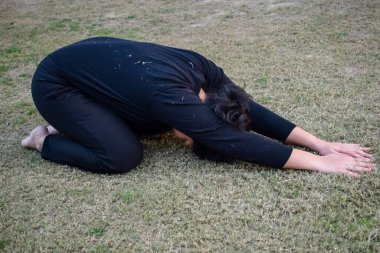 Young Indian woman practicing yoga outdoor in a park. Beautiful girl practice basic yoga pose. Calmness and relax, female happiness. Basic Yoga poses outdoor