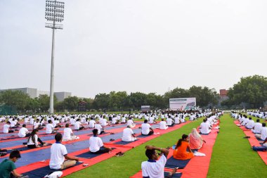 Yeni Delhi, Hindistan, 21 Haziran 2022 - Uluslararası Yoga Günü 'nde Delhi' deki Yamuna Spor Kompleksi 'nde grup Yoga egzersiz oturumu, kriket stadyumunda yoga derslerine katılan büyük bir grup yetişkin