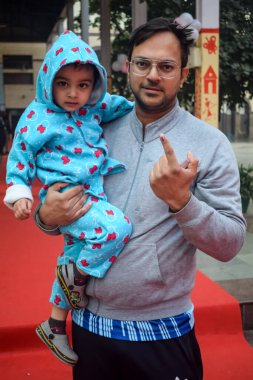 New Delhi, India - December 04 2022 - Unidentified people showing their ink-marked fingers after casting votes in front of polling booth of east Delhi area for MCD local body Elections 2022