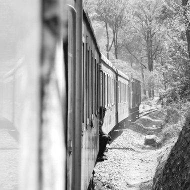 Oyuncak tren dağ yamaçlarında hareket ediyor, güzel bir manzara, bir dağ yamacı, bir vadi yamaçtan tepeye hareket ediyor, yeşil doğal ormanın arasında. Hindistan 'da Kalka' dan Shimla 'ya giden oyuncak tren, Hint treni.