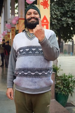 New Delhi, India - December 04 2022 - Unidentified people showing their ink-marked fingers after casting votes in front of polling booth of east Delhi area for MCD local body Elections 2022