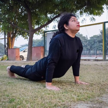 Young Indian woman practicing yoga outdoor in a park. Beautiful girl practice basic yoga pose. Calmness and relax, female happiness. Basic Yoga poses outdoor
