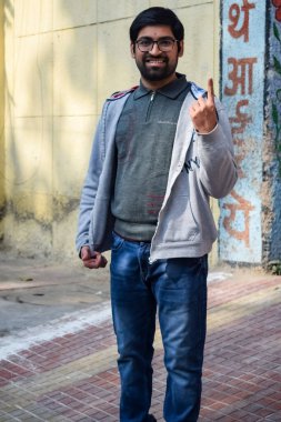 New Delhi, India - December 04 2022 - Unidentified people showing their ink-marked fingers after casting votes in front of polling booth of east Delhi area for MCD local body Elections 2022