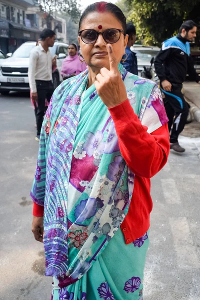 New Delhi, India - December 04 2022 - Unidentified people showing their ink-marked fingers after casting votes in front of polling booth of east Delhi area for MCD local body Elections 2022