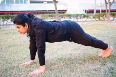 Young Indian woman practicing yoga outdoor in a park. Beautiful girl practice basic yoga pose. Calmness and relax, female happiness. Basic Yoga poses outdoor