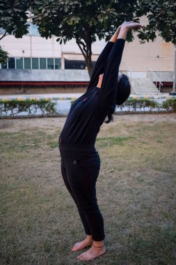 Young Indian woman practicing yoga outdoor in a park. Beautiful girl practice basic yoga pose. Calmness and relax, female happiness. Basic Yoga poses outdoor