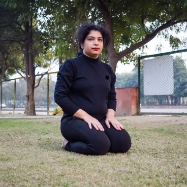 Young Indian woman practicing yoga outdoor in a park. Beautiful girl practice basic yoga pose. Calmness and relax, female happiness. Basic Yoga poses outdoor