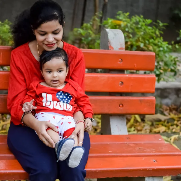 stock image Loving mom carrying of her baby at society park. Bright portrait of happy mum holding child in her hands. Mother hugging her little 9 months old son.