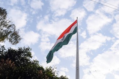India flag flying high at Connaught Place with pride in blue sky, India flag fluttering, Indian Flag on Independence Day and Republic Day of India, tilt up shot, Waving Indian flag, Har Ghar Tiranga