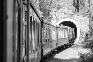 Oyuncak tren dağ yamaçlarında hareket ediyor, güzel bir manzara, bir dağ yamacı, bir vadi yamaçtan tepeye hareket ediyor, yeşil doğal ormanın arasında. Hindistan 'da Kalka' dan Shimla 'ya giden oyuncak tren, Hint treni.