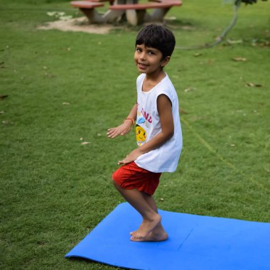 Sosyete parkında yoga pozu veren Asyalı zeki çocuk, çocuk yoga pozu. Yoga yapan küçük çocuk.