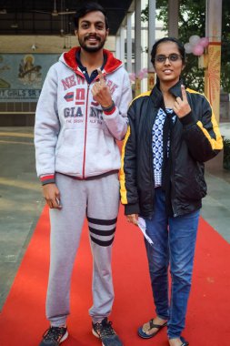 New Delhi, India - December 04 2022 - Unidentified people showing their ink-marked fingers after casting votes in front of polling booth of east Delhi area for MCD local body Elections 2022