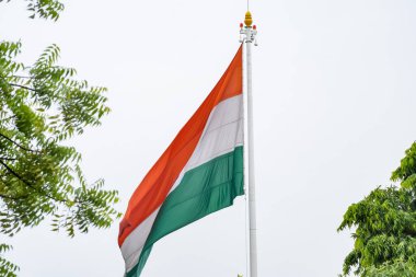 India flag flying high at Connaught Place with pride in blue sky, India flag fluttering, Indian Flag on Independence Day and Republic Day of India, tilt up shot, Waving Indian flag, Har Ghar Tiranga