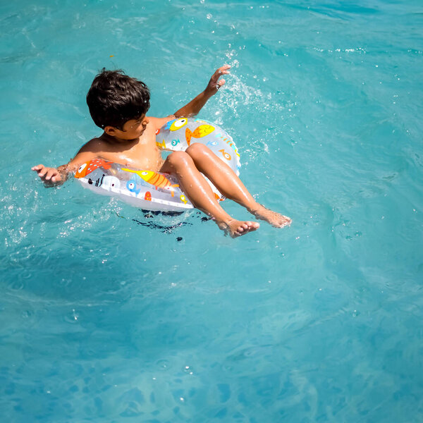 Счастливый индийский мальчик плавает в бассейне, Ребенок в купальном костюме вместе с воздуходувкой во время жарких летних каникул, Детский мальчик в большом бассейне.