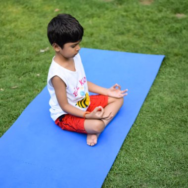 Sosyete parkında yoga pozu veren Asyalı zeki çocuk, çocuk yoga pozu. Yoga ve meditasyon yapan küçük çocuk..