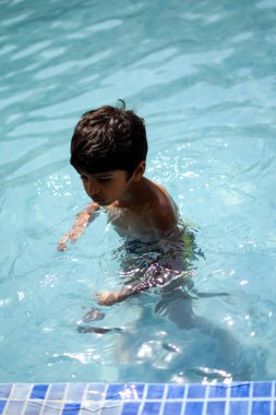 Havuzda yüzen mutlu Hintli çocuk, sıcak yaz tatillerinde hava tüpüyle birlikte yüzen çocuk, büyük bir havuzda yüzen çocuk..