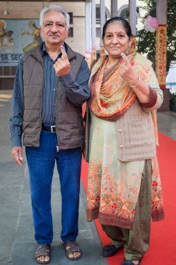 New Delhi, India - December 04 2022 - Unidentified people showing their ink-marked fingers after casting votes in front of polling booth of east Delhi area for MCD local body Elections 2022