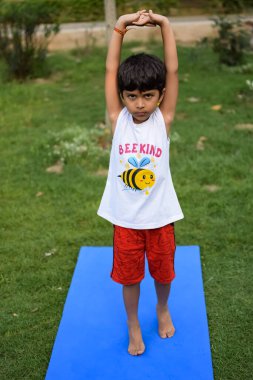 Sosyete parkında yoga pozu veren Asyalı zeki çocuk, çocuk yoga pozu. Yoga ve meditasyon yapan küçük çocuk..
