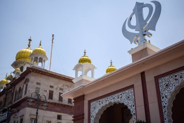 Gurudwara girişinde Khanda Sikh kutsal dini sembolü parlak mavi gökyüzü görüntüsüyle Chandni Chowk 'ta, Eski Delhi' deki Kızıl Kale 'nin karşısındaki Sis Ganj Sahib Gurudwara' da çekildi.