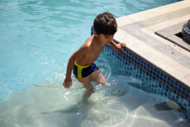 Havuzda yüzen mutlu Hintli çocuk, sıcak yaz tatillerinde hava tüpüyle birlikte yüzen çocuk, büyük bir havuzda yüzen çocuk..