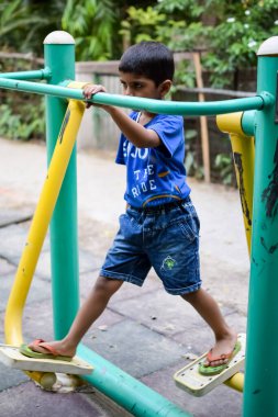 Asyalı çocuk sabah vakti sosyete parkında rutin egzersiz yapıyor. Kendini hayat boyu zinde tutmak için şirin bir çocuk egzersizi ve spor salonu. Açık havada çocuk egzersizi.
