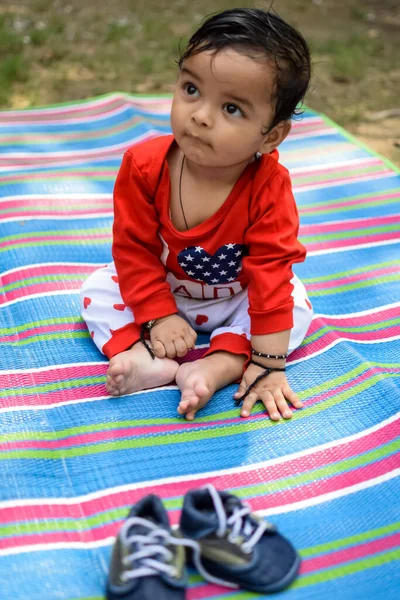 在德里的社会公园里 可爱的印度婴儿坐在户外拍摄 可爱的男婴坐在五彩缤纷的垫子上 身边撒满青草 男婴坐在室外拍摄 — 图库照片