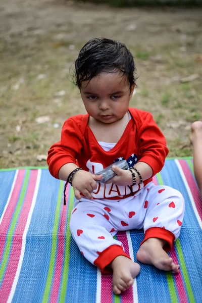 在德里的社会公园里 可爱的印度婴儿坐在户外拍摄 可爱的男婴坐在五彩缤纷的垫子上 身边撒满青草 男婴坐在室外拍摄 — 图库照片