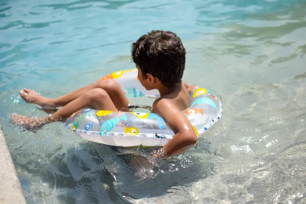 stock image Happy Indian boy swimming in a pool, Kid wearing swimming costume along with air tube during hot summer vacations, Children boy in big swimming pool.