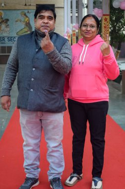 New Delhi, India - December 04 2022 - Unidentified people showing their ink-marked fingers after casting votes in front of polling booth of east Delhi area for MCD local body Elections 2022