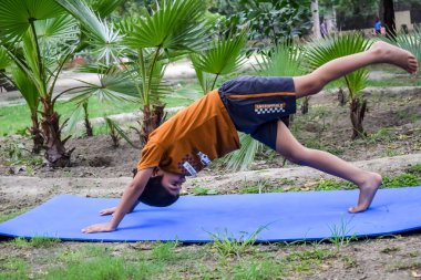 Sosyete parkında yoga pozu veren Asyalı zeki çocuk, çocuk yoga pozu. Yoga ve meditasyon yapan küçük çocuk..