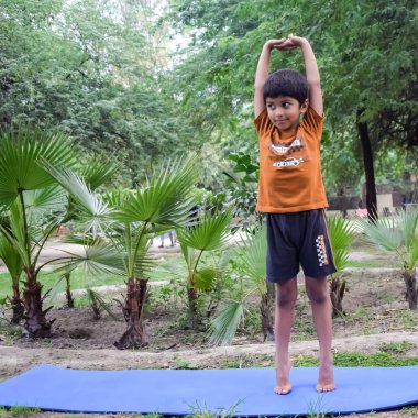 Sosyete parkında yoga pozu veren Asyalı zeki çocuk, çocuk yoga pozu. Yoga ve meditasyon yapan küçük çocuk..