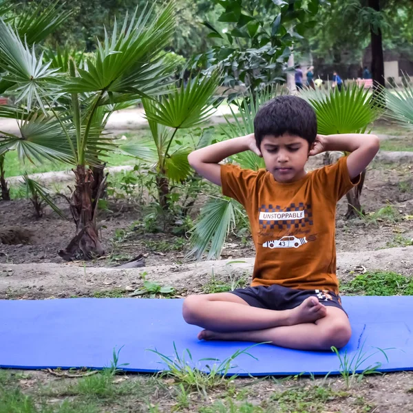 Sosyete parkında yoga pozu veren Asyalı zeki çocuk, çocuk yoga pozu. Yoga ve meditasyon yapan küçük çocuk..