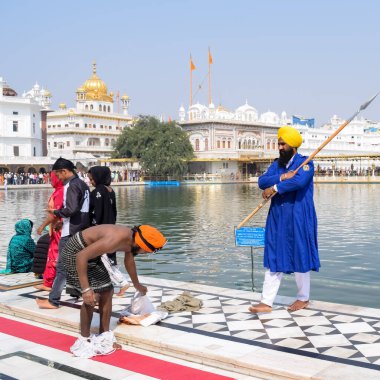 Amritsar, Hindistan - 26 Şubat 2023 - Amritsar, Punjab, Hindistan 'daki Altın Tapınak' ta (Harmandir Sahib) sarovarda kutsal dalış yapan tanımlanamayan dindarlar,